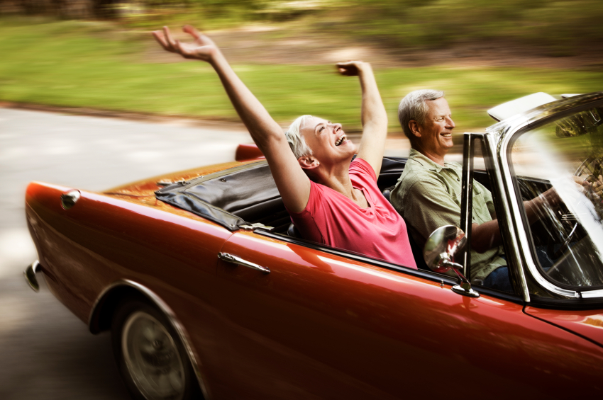 elderly woman holding hands up in convertible
