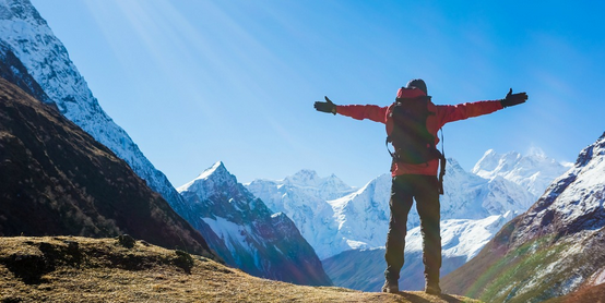 hiker holding arms straight out in front of mountain