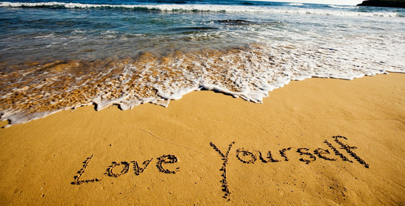 love yourself written in sand on beach