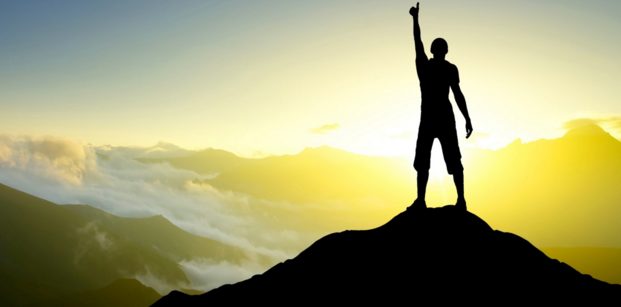 silhouette of person raising arm on mountain top