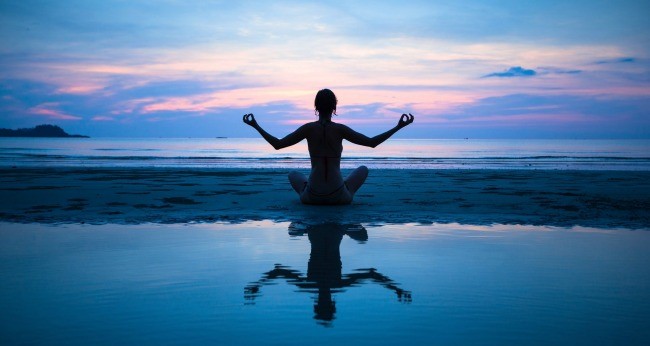 woman meditating on beach with reflection