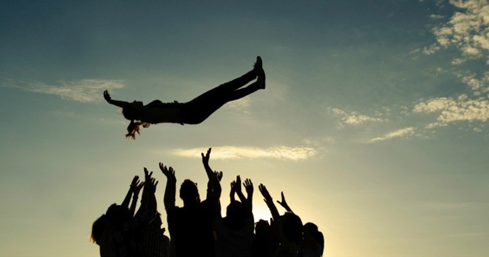 silhouette of people throwing someone in air