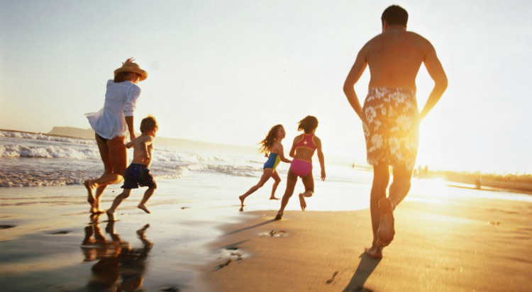 family running on beach during sunset