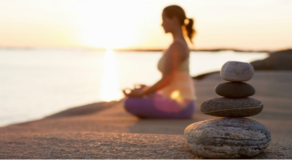 person meditating behind stacked rocks