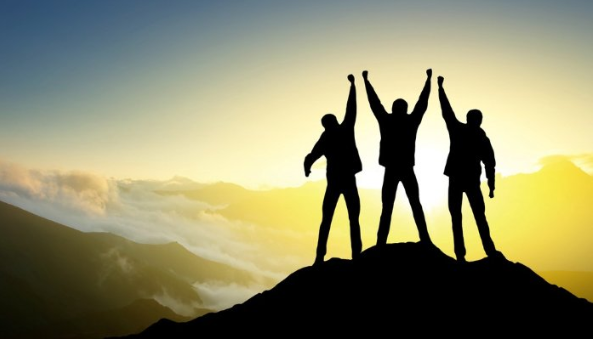 silhouettes of people cheering on mountain