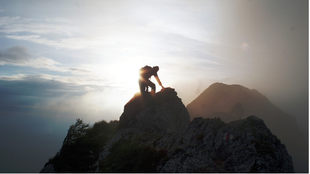 silhouette of man climbing mountain